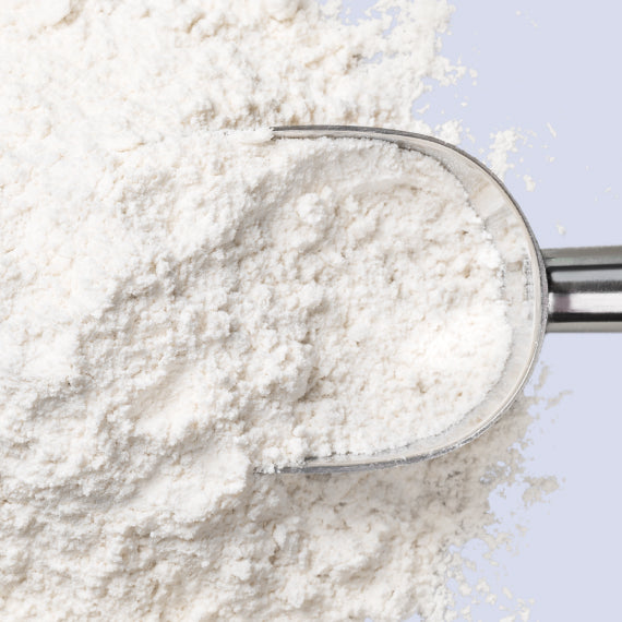 Close-up of acetyl-L-carnitine powder on a table. The powder is white and fine in texture. Acetyl-L-carnitine is a PCOS supplement often used to help manage PCOS symptoms by supporting energy levels, improving insulin sensitivity, and promoting healthy metabolism