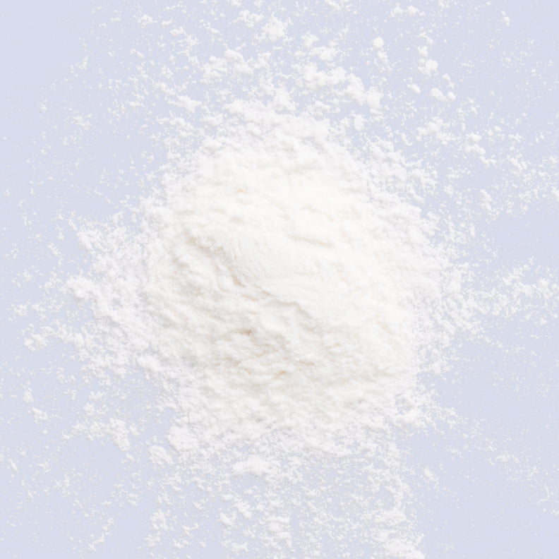 Close-up of inositol powder scattered on a table. The powder is white and fine in texture. Inositol is a popular PCOS supplement known for helping manage PCOS symptoms, particularly by regulating insulin levels and supporting ovarian function