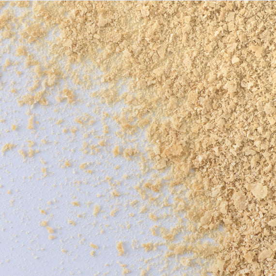 Close-up of flaky, brown biotin powder scattered on a table. The powder has a coarse texture and a rich brown color. Biotin is a popular PCOS supplement often used to help manage PCOS symptoms, particularly by supporting healthy hair growth and improving metabolic function
