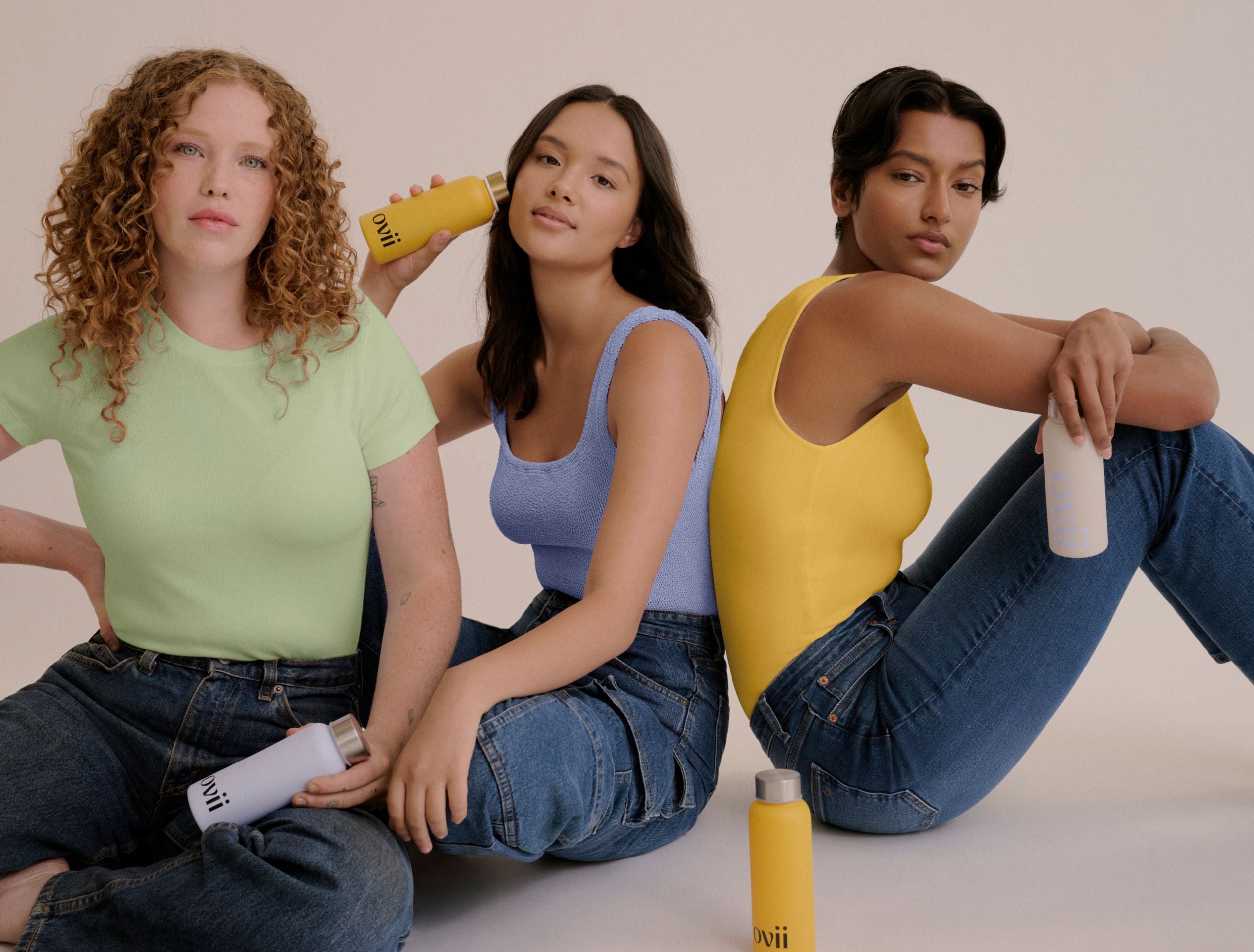 Three women sitting together, each holding a bottle of Ovii supplement. They smile and appear confident, showcasing a sense of empowerment. The image suggests how the Ovii supplement, designed to support women's health, may help manage PCOS symptoms. Their positive expressions reflect the potential benefits of the PCOS supplement in supporting overall well-being.