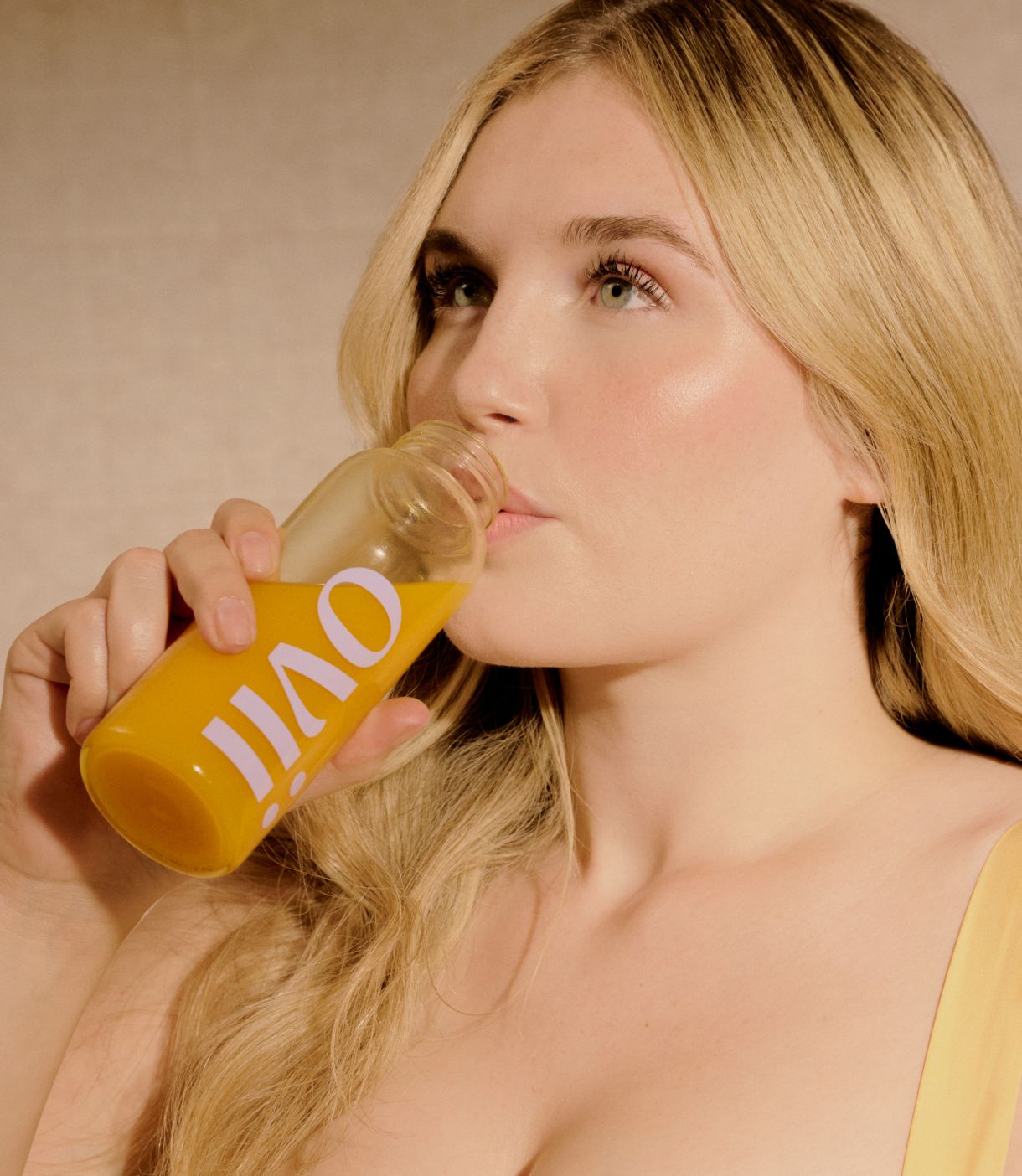 A woman is drinking from a bottle of Ovii supplement, looking content and focused. The image highlights her enjoying the supplement, which is designed to support women's health and may help manage PCOS symptoms. Her calm expression reflects the potential benefits of the PCOS supplement in promoting overall well-being.